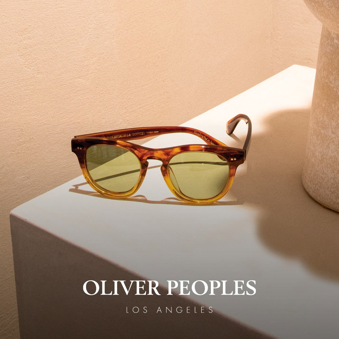 Das Bild zeigt eine braune Oliver Peoples Sonnenbrille auf einer Fläche vor einer terracottafarbenen Wand.