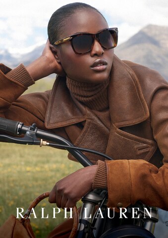 Das Bild zeigt eine jugne Frau mit Sonnenbrille, die sich über den Lenker eines Fahrrades lehnt.