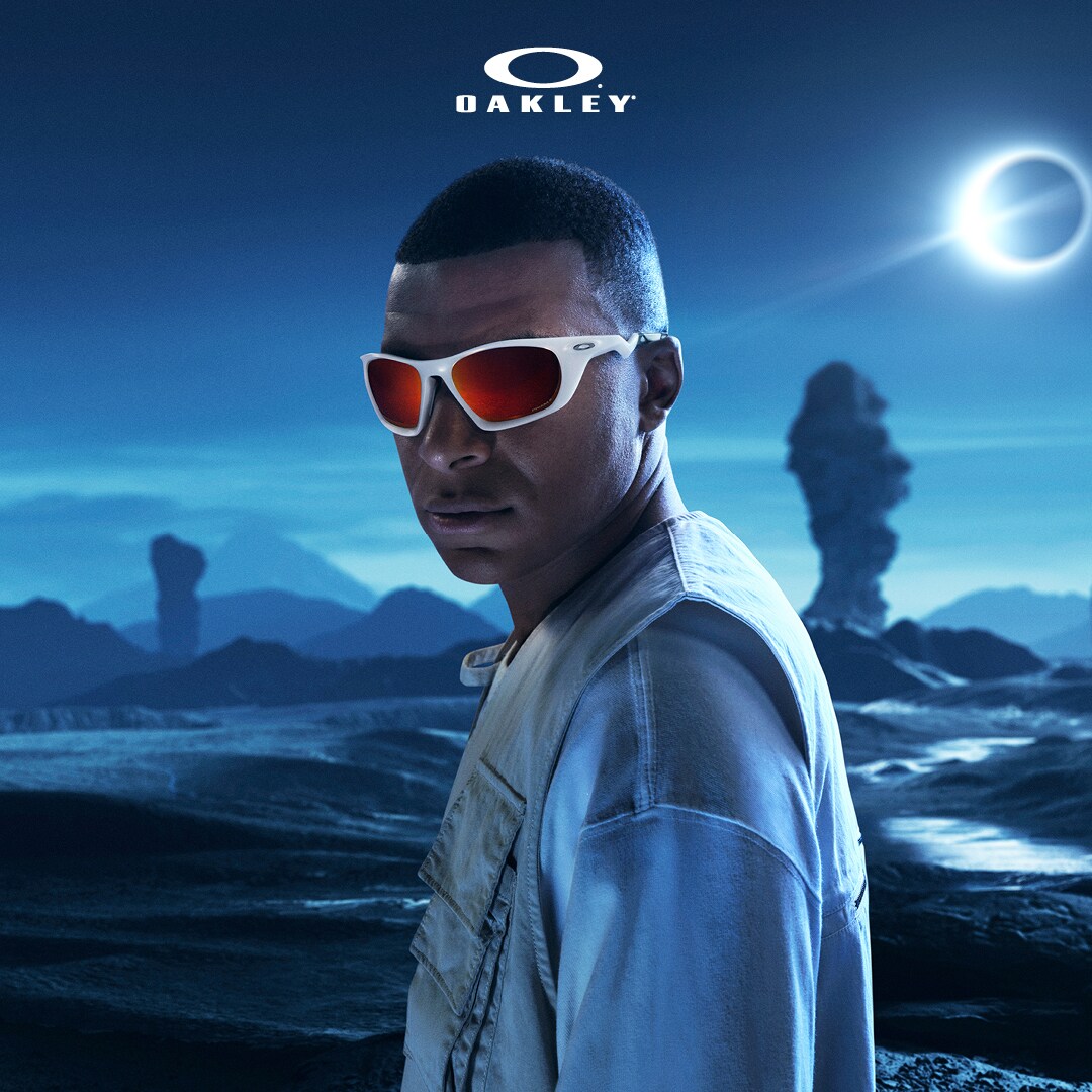 Das Bild zeigt Kylian Mbappé mit Sonnenbrille vor einem dunklen Hintergrund.